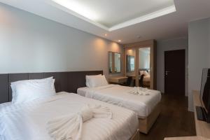 邦波Tisha Hotel的一间卧室配有两张带白色床单的床