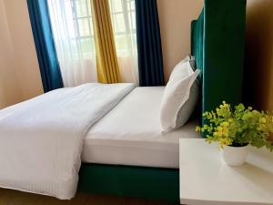 EmbuTwo bedroom Paradise Apartment Embu的一张带绿色床头板的床,靠窗