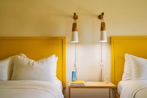 棕榈泉棕榈泉瑟括洛酒店的酒店客房设有两张床、一张桌子和两盏灯。