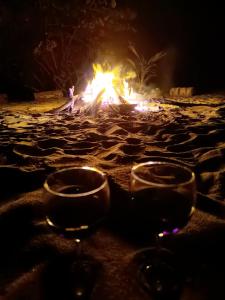 GuachacaSierra Sagrada Tayrona的两杯酒杯坐在海滩上,火炉旁