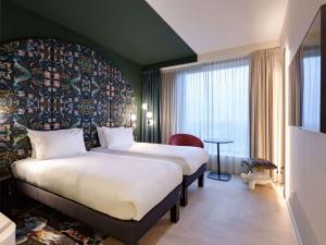 鹿特丹ibis Styles Rotterdam Ahoy的酒店客房设有两张床和大窗户。