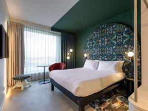 鹿特丹ibis Styles Rotterdam Ahoy的酒店客房设有一张大床和一张桌子。
