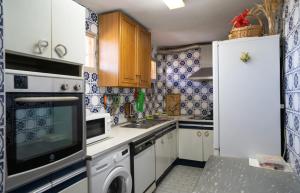 贝纳尔马德纳Habitación doble con baño compartido en Benalmadena的厨房配有白色橱柜和蓝色及白色瓷砖