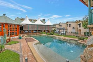 TinarooHaven- Lake Tinaroo Resort的一座游泳池,位于一座带建筑物的庭院内