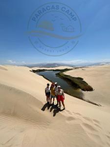帕拉卡斯"Paracas Camp"的三人站在沙丘顶上