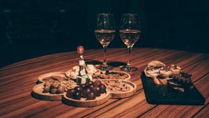 马查利亚Hostería del Parque的一张木桌,上面放着两杯葡萄酒和食物
