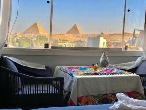 开罗Three pyramids view INN的一间设有一张桌子的房间,享有金字塔的景色
