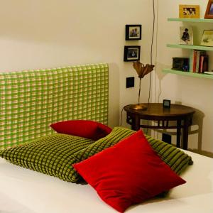 都灵Apart Deluxe Casa Boffa-Costa的一张带两个红色枕头和桌子的床