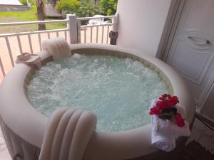 三河市VillaBadlou "Lodge Ti-Kaco Vanille"的阳台上的热水浴缸,里面装有鲜花