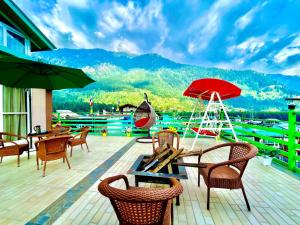 马拉里Vista Resort, Manali - centrally Heated & Air cooled luxury rooms的一个带桌椅的甲板和红色遮阳伞