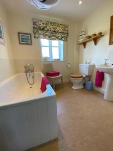 比明斯特Lower Farm Cottage的带浴缸、卫生间和盥洗盆的浴室