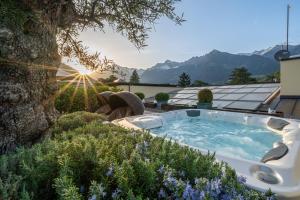梅拉诺Hotel Mignon Meran Park & Spa的花园内的一个热水浴池,以群山为背景