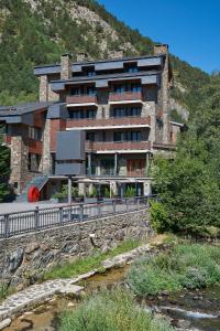 马萨纳NH Collection Andorra Palomé的山丘上的建筑物,前面有一条河流