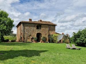 锡纳伦加Podere Pievina Delle Corti - Dimora di Campagna的一座古老的石头建筑,在田野上设有长凳