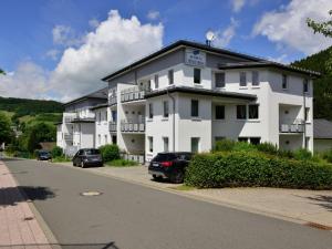 维林根Magnificent Apartment in Willingen with Balcony的一座白色的建筑,前面有汽车停放