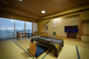 鹤冈市尤拉温泉八乙女日式旅馆 的客厅配有桌子,享有海景