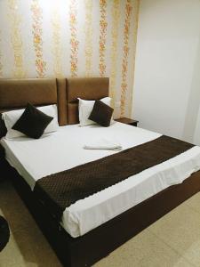 新德里Hotel Ambience Palace Near IGI Airport Delhi的一张配有白色床单和枕头的大床
