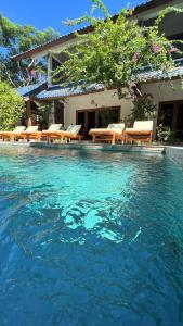 吉利特拉旺安Marygio Gili Resort的房屋前设有带桌椅的游泳池