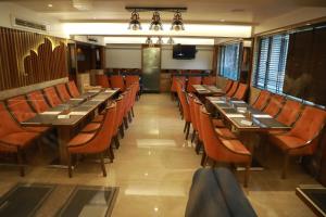 孟买HOTEL ARCHANA RESIDENCY的用餐室配有长桌子和橙色椅子