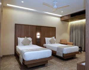 孟买HOTEL ARCHANA RESIDENCY的酒店客房,配有两张床和椅子