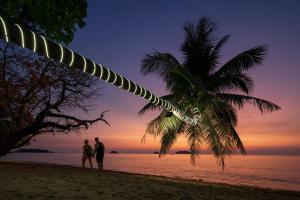 象岛GajaPuri Resort Koh Chang的两个人站在一个棕榈树海滩上