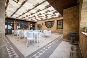马里内拉La Rosa Hotel - Selinunte的大楼内带白色桌椅的庭院