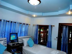 罗勇素克索姆亚酒店的一间卧室配有床、电视和蓝色窗帘
