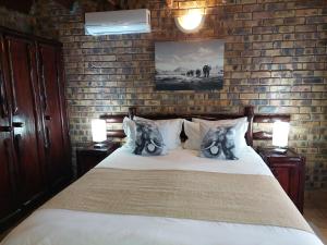 玛洛斯帕克Khumbula iAfrica 1的一间卧室配有一张带两盏灯和砖墙的床。