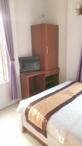 河内Ks Huy Hoang Airport的一间卧室配有一张床和一个带电视的梳妆台。