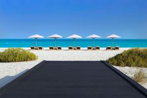 阿布扎比阿布扎比柏悦酒店别墅的通往海滩的步道,配有椅子和遮阳伞