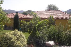 ButreraEl Refugio de Santi的一座黄色的房子,里面有许多树木和灌木