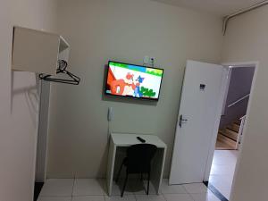 LagartoPOUSADA MEDITERRÂNEO的客房设有书桌和墙上的电视
