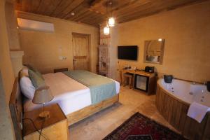 乌奇希萨尔Milagro of Cappadocia的一间卧室配有一张床、一个浴缸和一台电视。