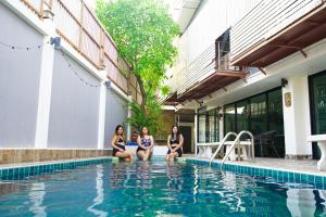 南芭堤雅Exotica Pool Villa Encore的三个女人坐在游泳池旁边