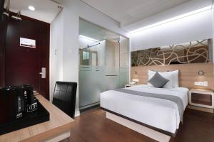 泗水Hotel Neo Gubeng by ASTON的卧室配有白色的床和电视。