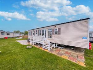 大雅茅斯By The Seaside Dog Friendly Caravan At Haven Hopton In Norfolk Ref 80015w的草坪上带门廊的大型金属拖车