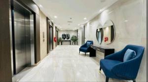 拉合尔Premium 1BR DHA Phase 5的走廊设有蓝色椅子、书桌和镜子