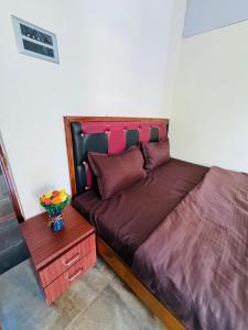 ParxemSerenity Homes的一张带紫色床单的床和一张带花瓶的桌子