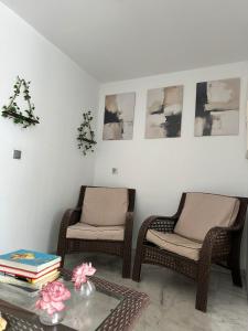 奇皮奥纳APARTAHOTEL DOÑA REYES的客厅配有2把藤椅和1张桌子