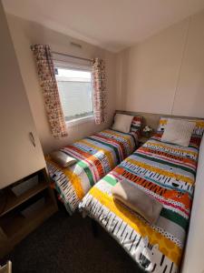 UlromeCosy Caravan的带窗户的客房内设有两张单人床。