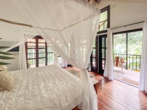 Big CreekCasa de Mono Bocas的一间卧室配有一张带天蓬的白色床