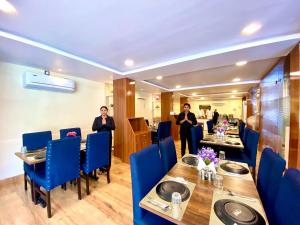 商沙巴Hotel Sky International- Airport Zone Hyderabad的两人在带桌子和蓝色椅子的餐厅