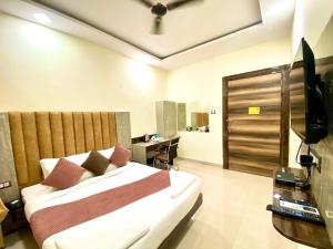 商沙巴Hotel Sky International- Airport Zone Hyderabad的一间卧室配有一张床、一张书桌和一台电视