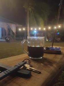 卡里蒙贾瓦JN Cottage dan Camping Ground的坐在桌子上边,一边喝咖啡一边拿钥匙