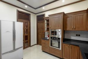 FuvahmulahAlafehi Retreat的厨房配有木制橱柜和白色冰箱。