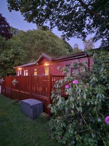 温德米尔Windermere lodge,sleeps 6的红色小屋,设有围栏和粉红色的鲜花