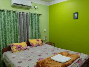 西里古里Anjali BnB Homestay的绿色墙壁客房的一张床位