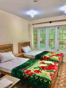 锡卡都Al Jannat Hotel & Relax Inn Guest House Skardu的一间卧室设有两张床和窗户。