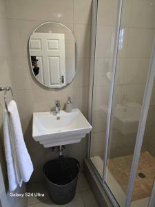 德班Durban Muslim/Halaal Accomdation的一间带水槽、淋浴和镜子的浴室