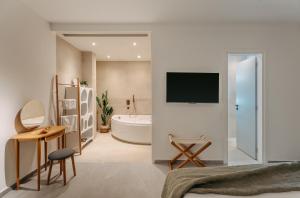 特里佐尼亚Trizonia Mare Suites的一间卧室设有带浴缸的浴室和电视。